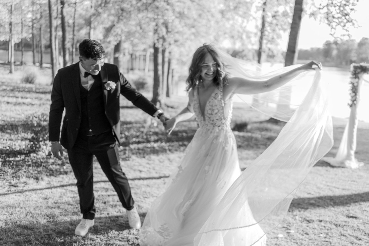 Romantic outdoor wedding photo session with flowing white dress in natural setting.