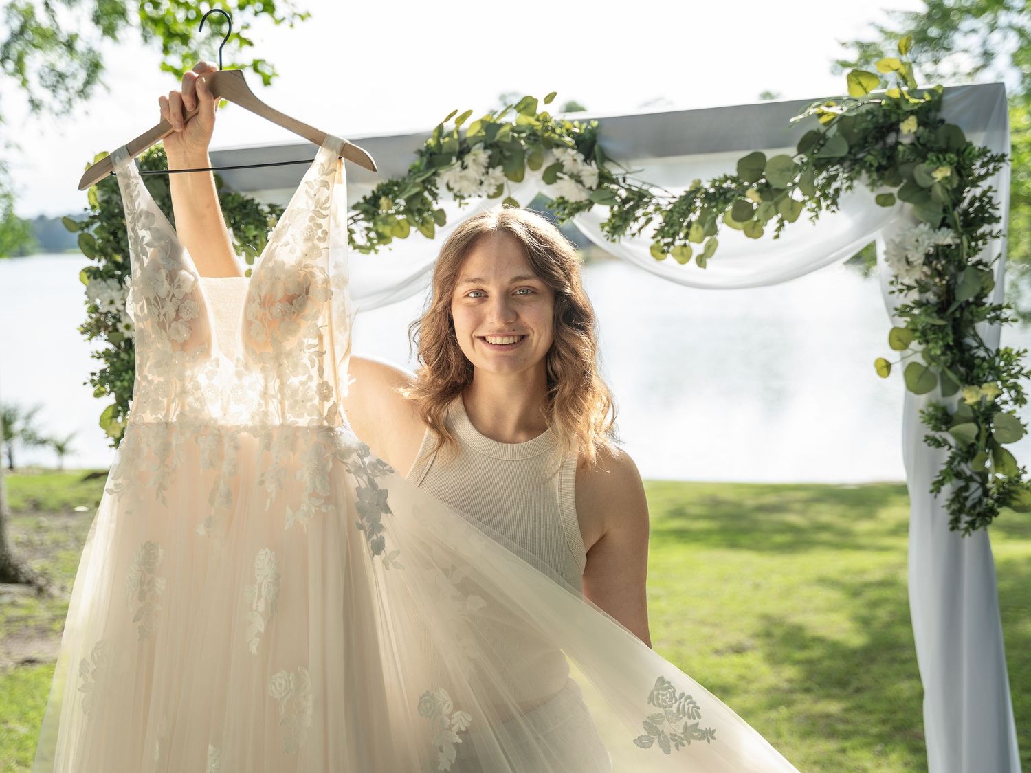 White wedding dresses hang elegantly on display under a covered outdoor porch with greenery.