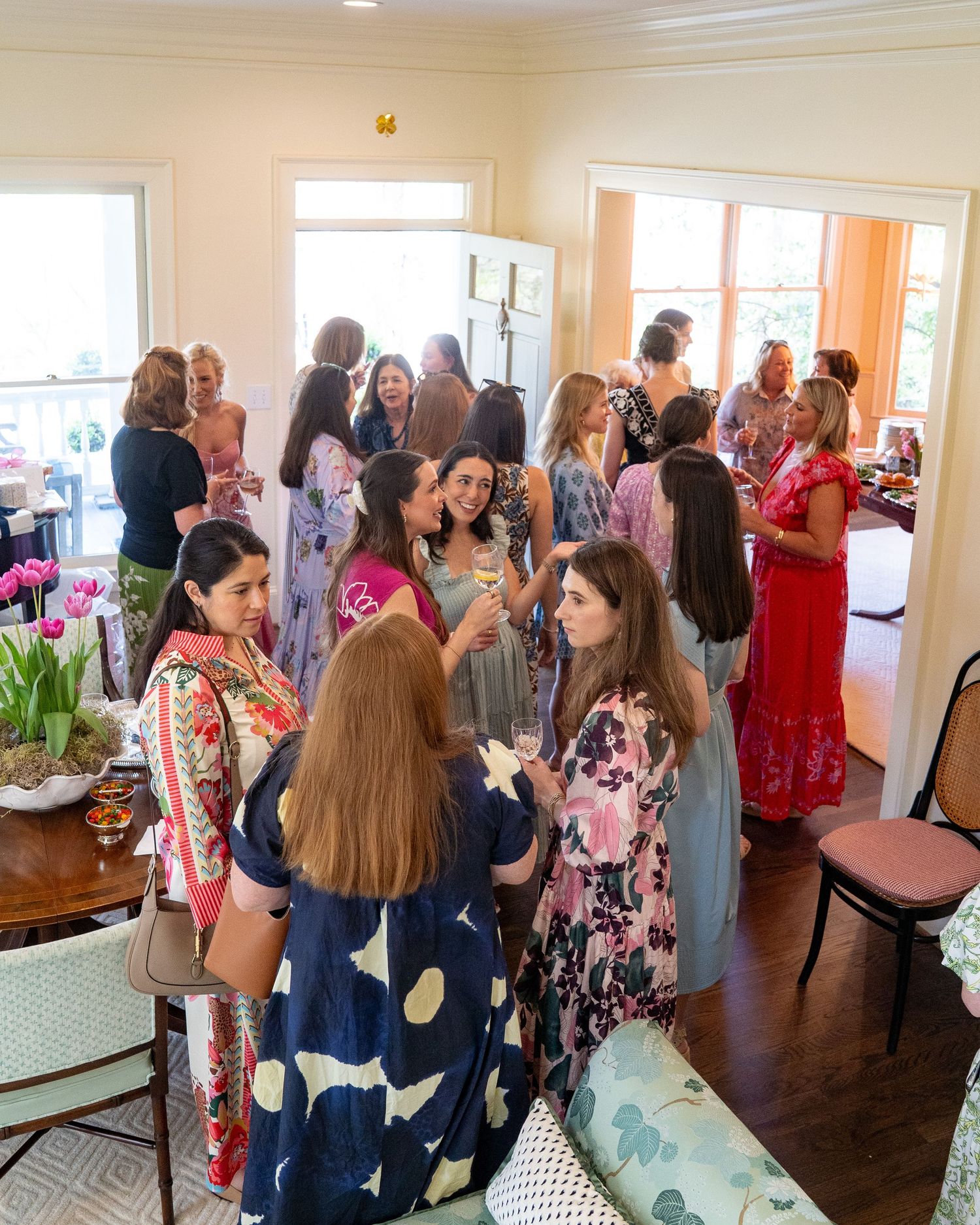 A group of elegantly dressed women mingling and socializing at an indoor gathering or bridal shower event.