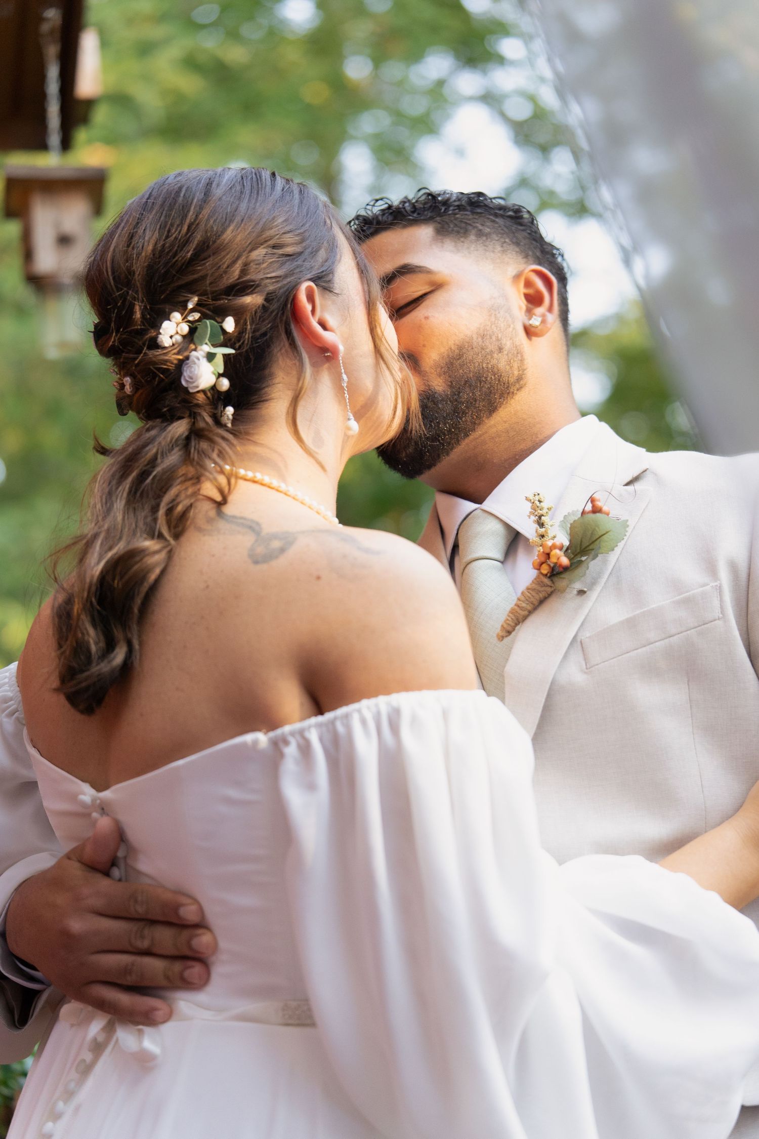 A romantic outdoor embrace between two people dressed in white.