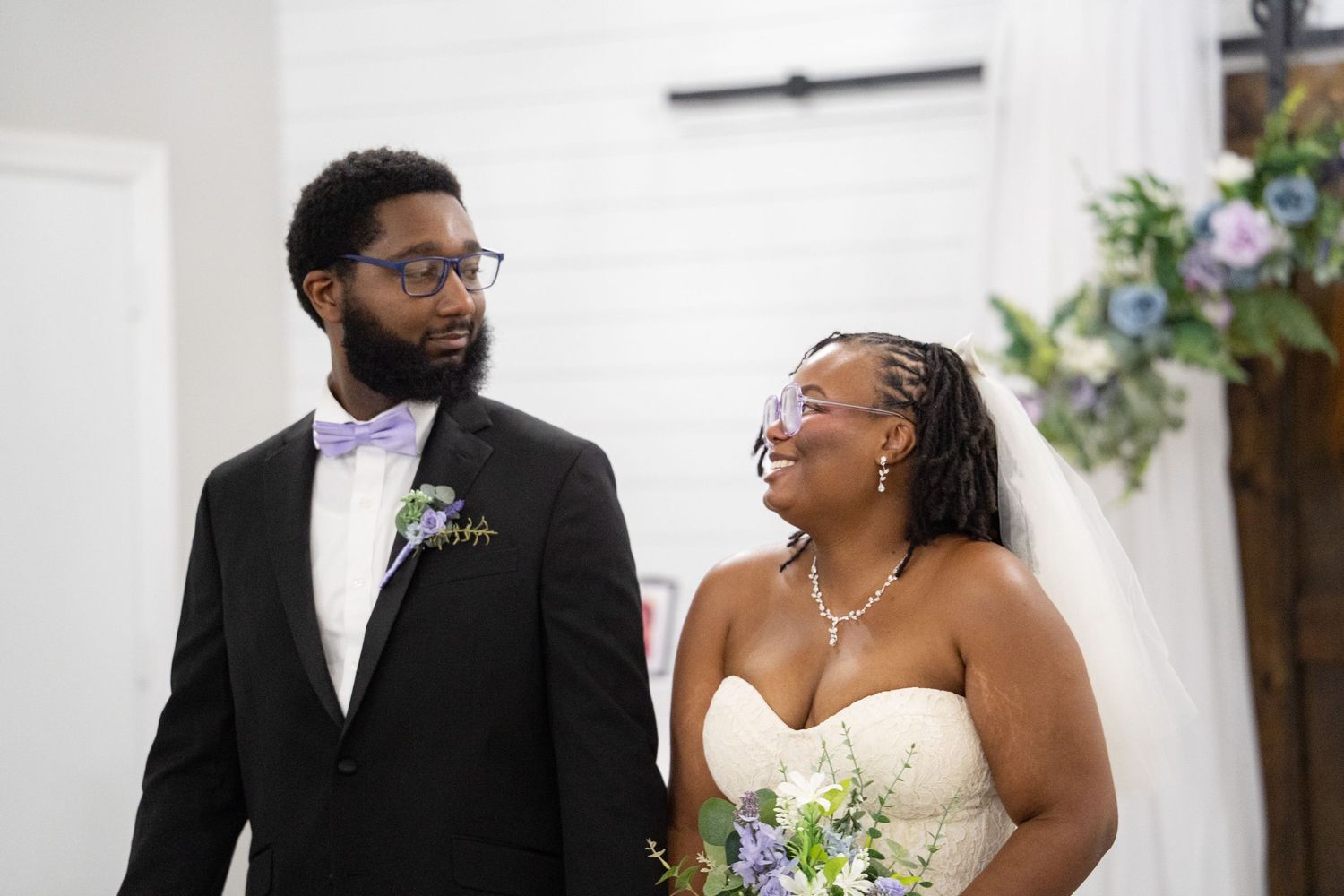 Wedding ceremony photos showing tender moments between a couple in front of wooden doors.