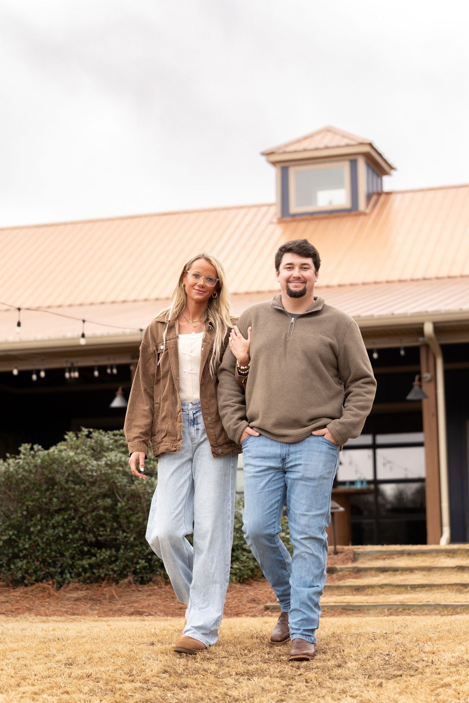 A couple walking and laughing together on a sunny day outside a building with a copper roof.