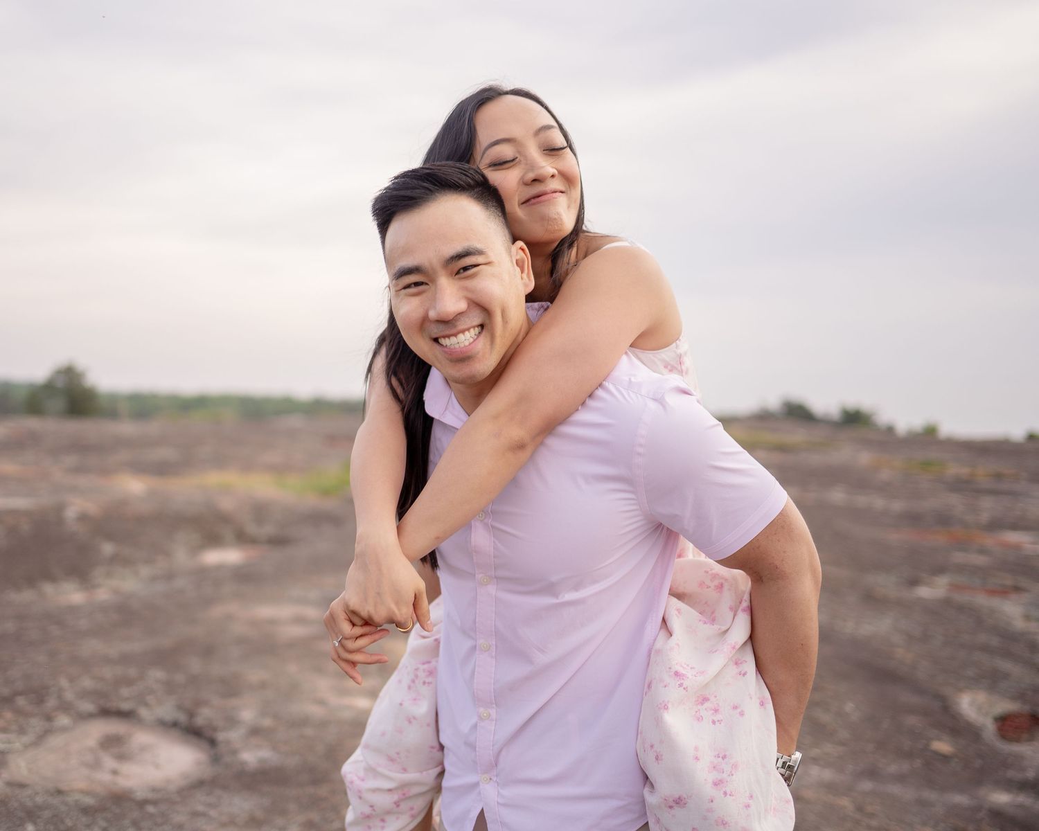 Playful engagement photos of a couple in light colored outfits against a desert landscape.