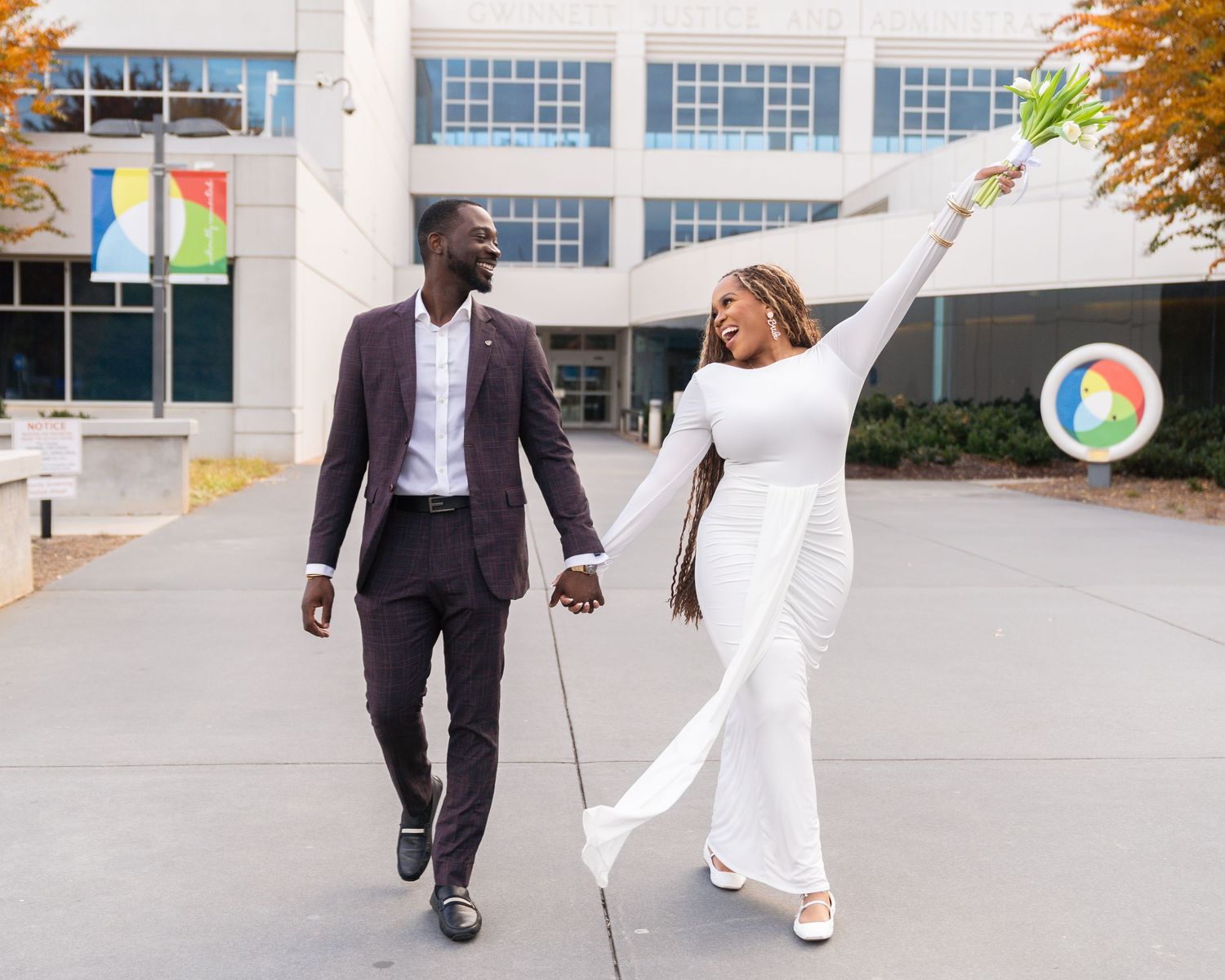 A couple dances and spins together outside a modern building with large windows.