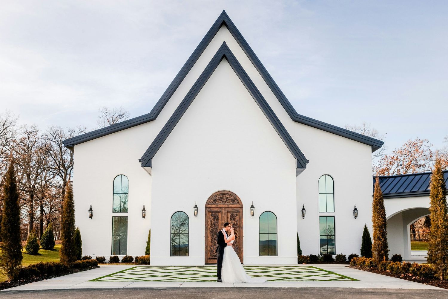 Bride and groom kissing in front of a stunning white chapel wedding venue.