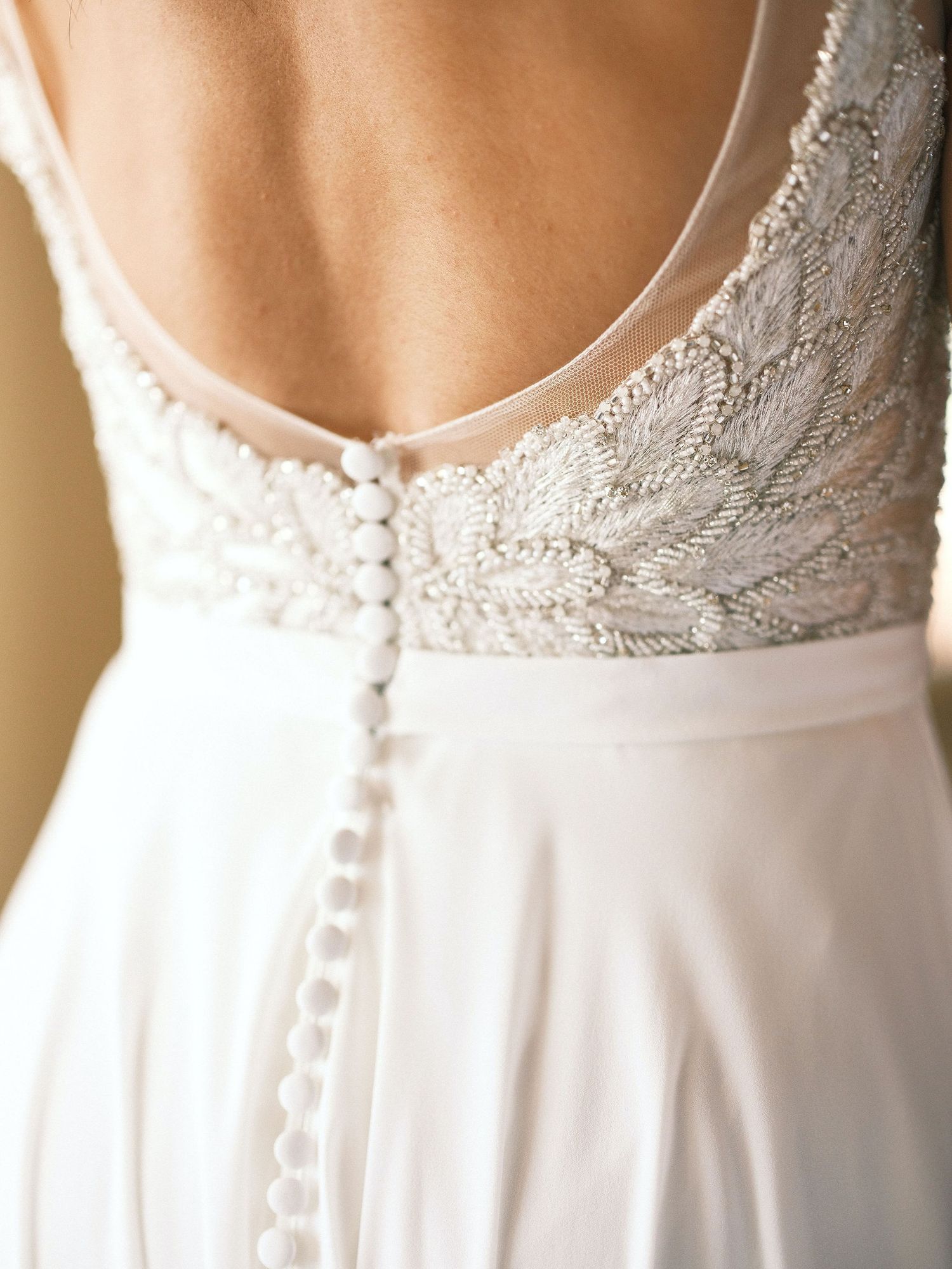Close-up of intricate beaded lace back detail on a beautiful white wedding gown.