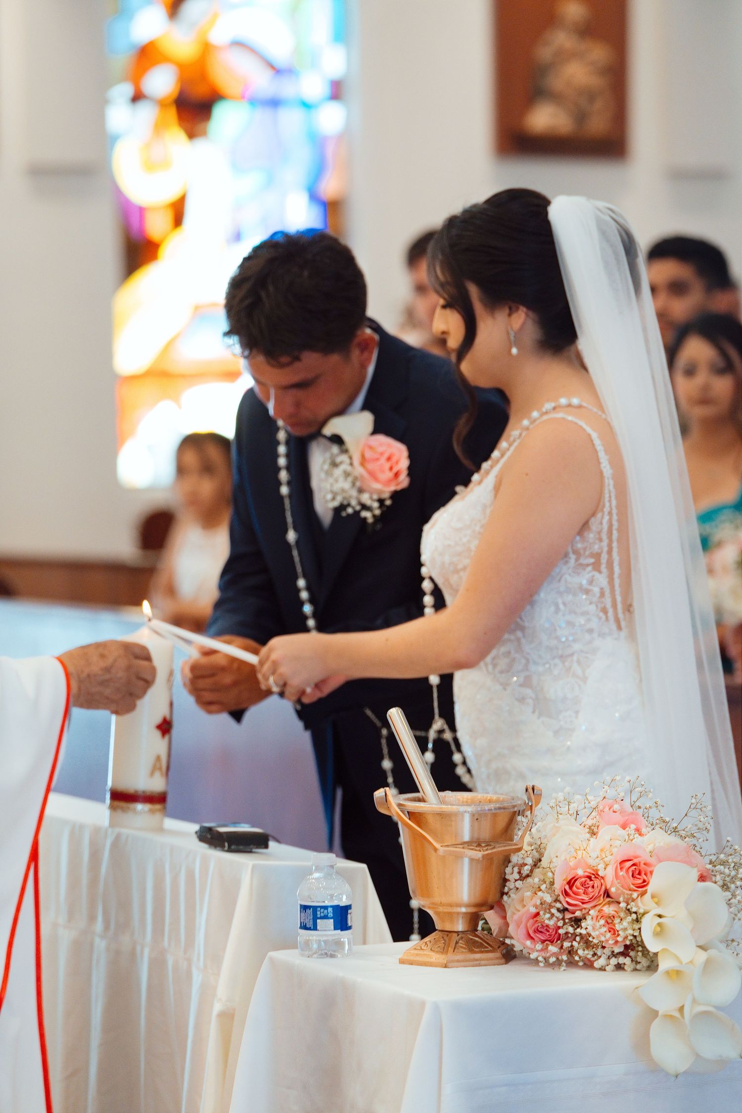 Bride and groom exchanging vows at church altar during Catholic wedding ceremony with floral bouquet.