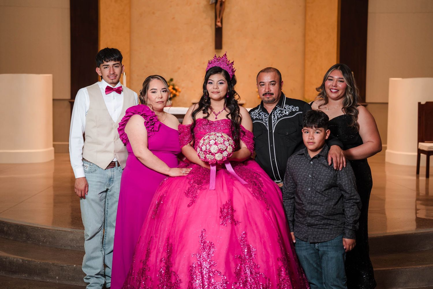Family group portrait at a quinceañera with the birthday girl in a stunning hot pink ball gown.