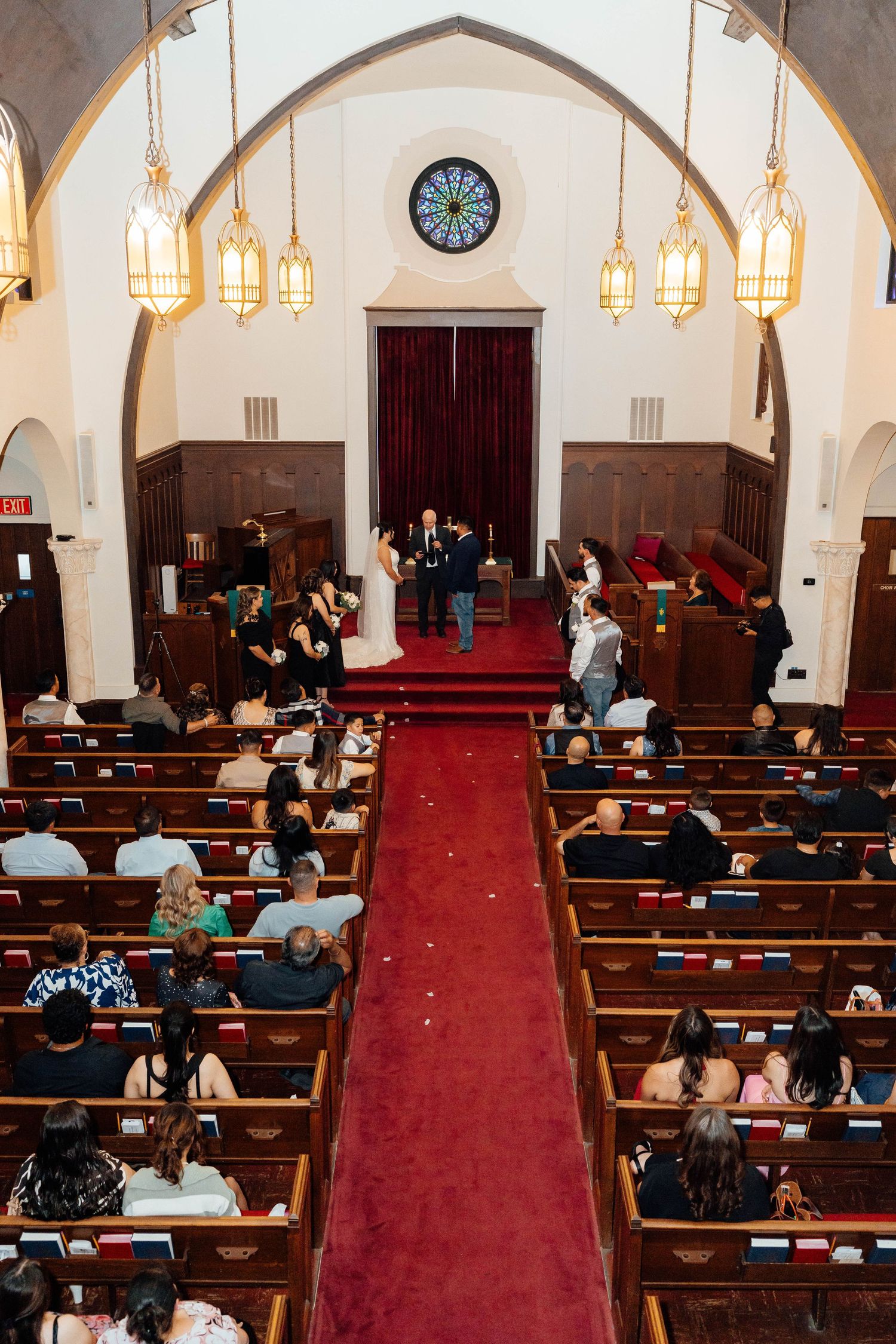 Wide aerial view of wedding ceremony in church with red carpet aisle.