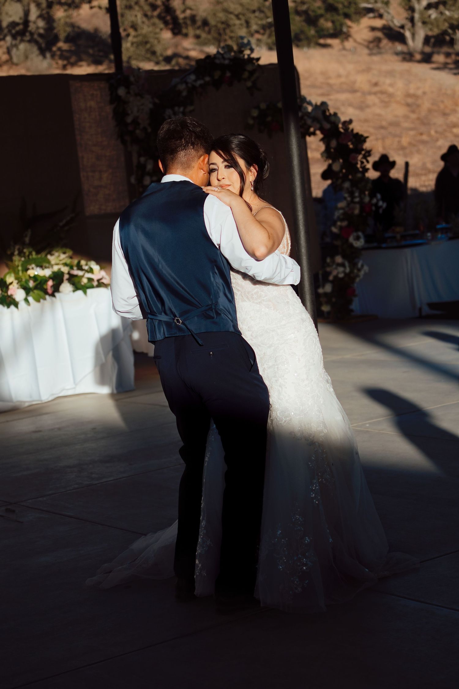 Bride and groom share intimate first dance in warm sunlight at outdoor wedding reception.