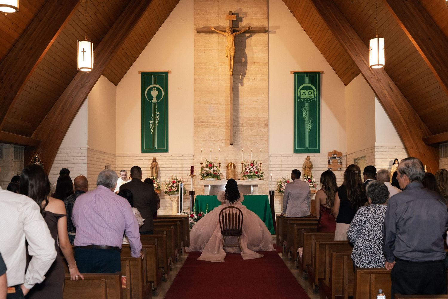 Congregation kneels before a crucifix at a Catholic church altar during a solemn religious service.