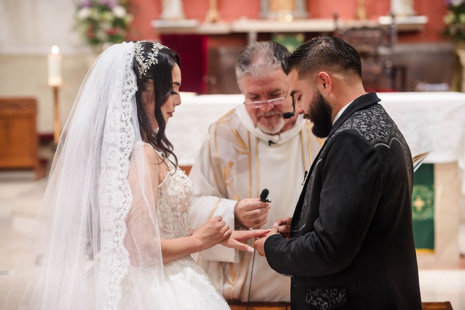 Bride and groom exchanging rings during a traditional church wedding ceremony with priest officiating.