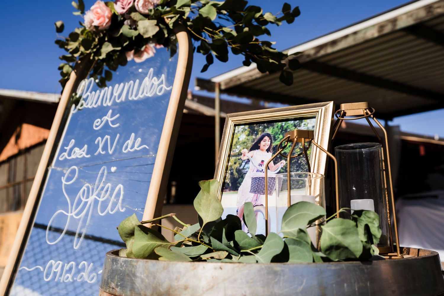 Elegant quinceañera welcome sign with floral decorations and a framed photo for Sofea's XV celebration.