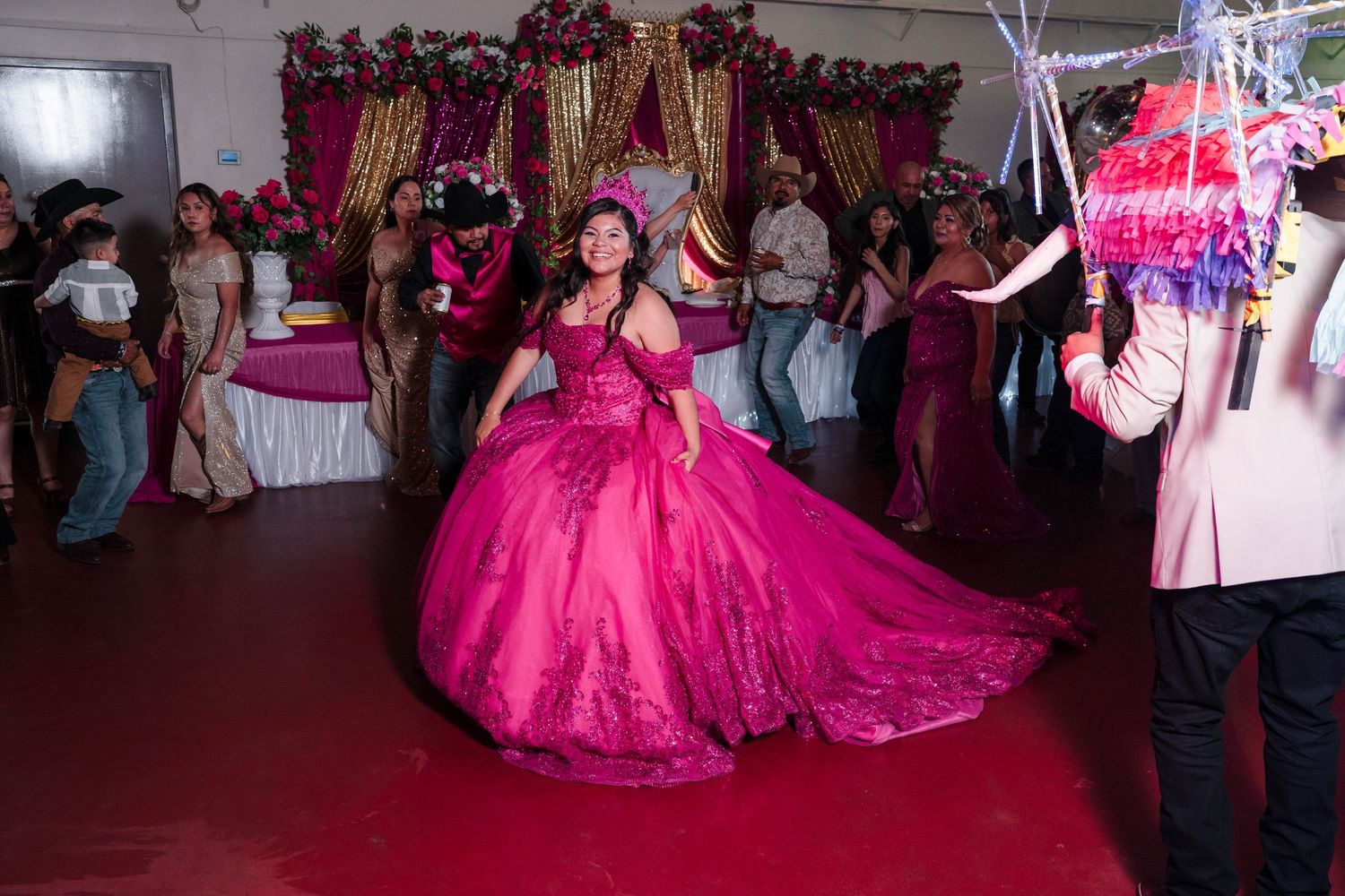 Quinceañera girl twirls in her hot pink ball gown on the dance floor at her festive celebration.
