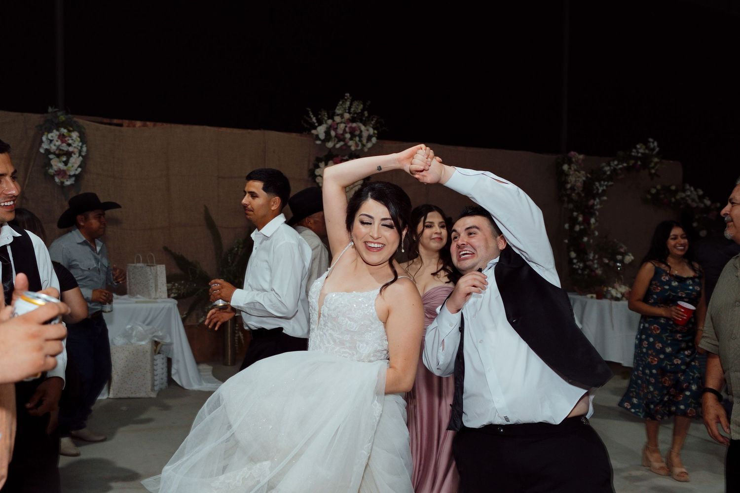 Bride in white gown dancing with groom in black suit at wedding reception celebration.