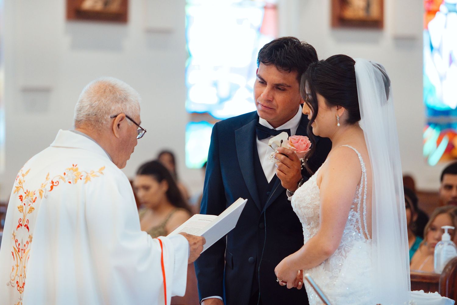 Bride and groom exchanging vows with a priest during a traditional church wedding ceremony.