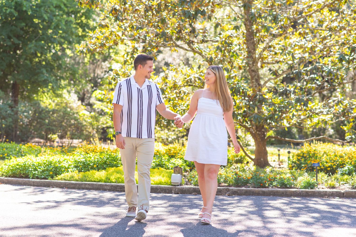 Happy couple holding hands and walking together in a sunny park with golden trees.