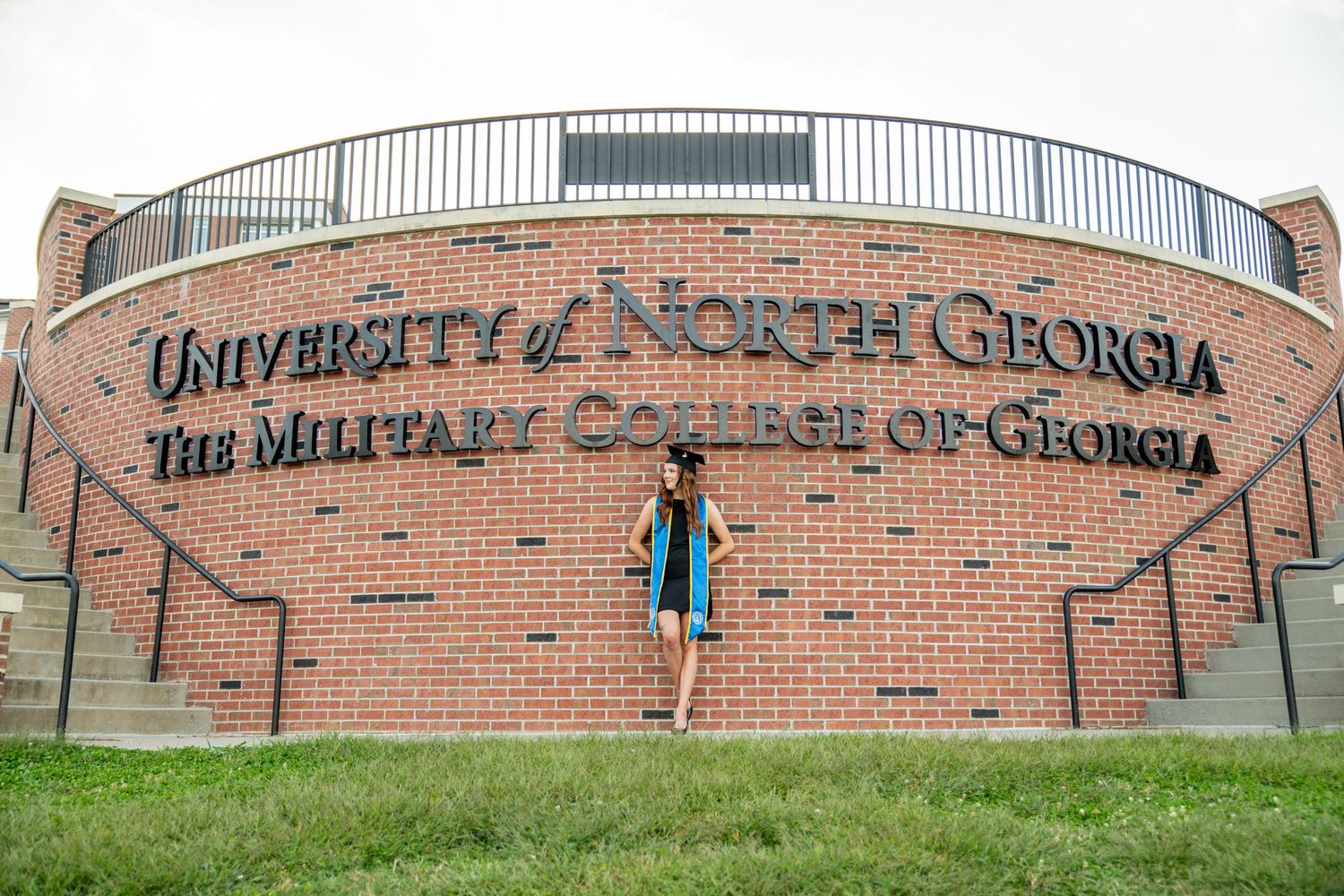 Student posing in front of University of North Georgia, The Military College of Georgia brick sign on campus.