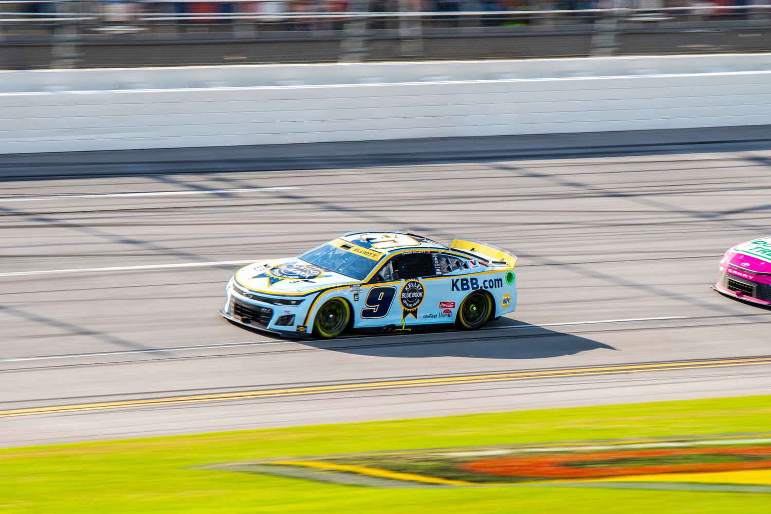 NASCAR race car number 9 speeding on a superspeedway track during a daytime race. Chase Elliott