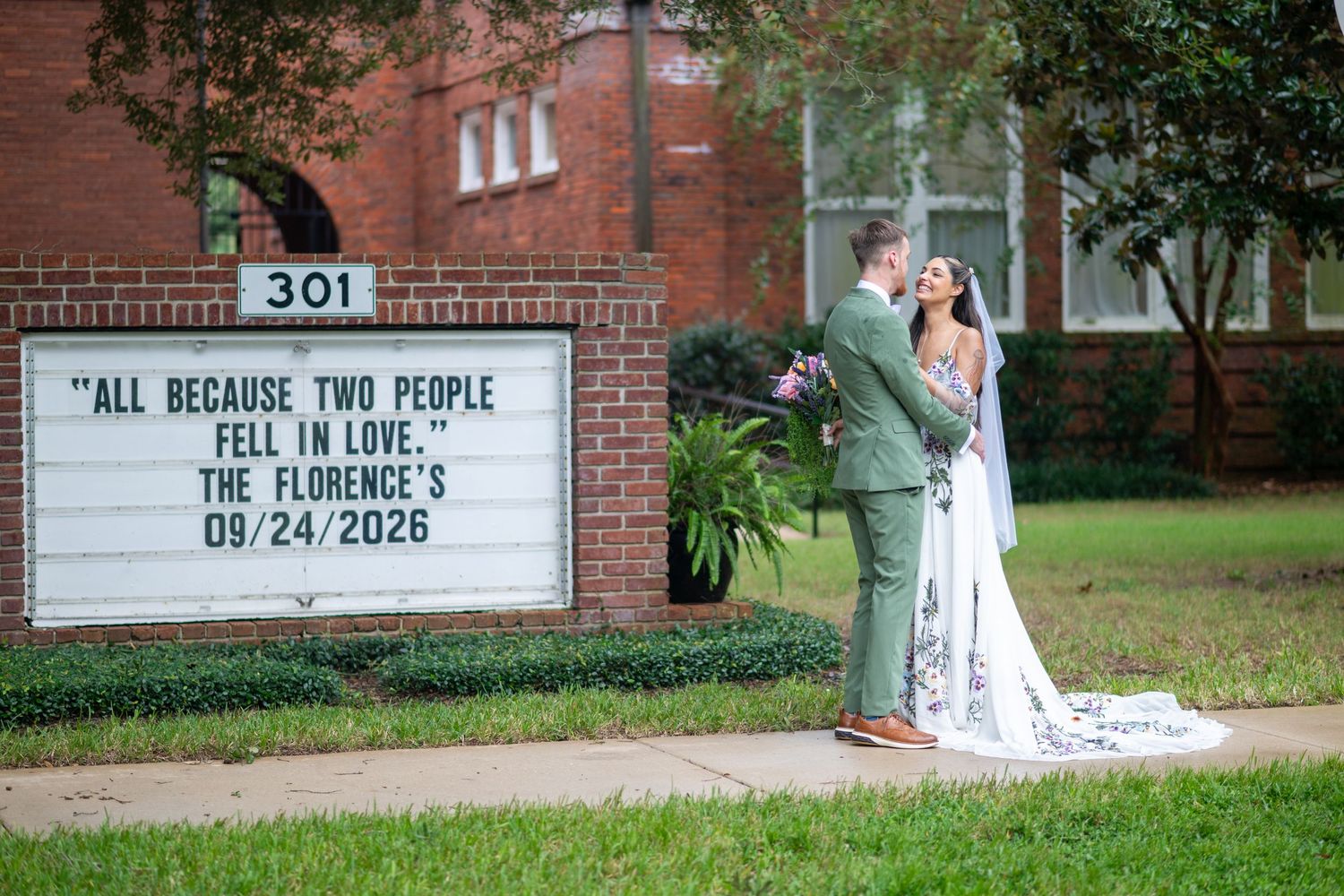 Newlywed couple poses by a church marquee sign reading All Because Two People Fell in Love, The Florences 09/24/2026.