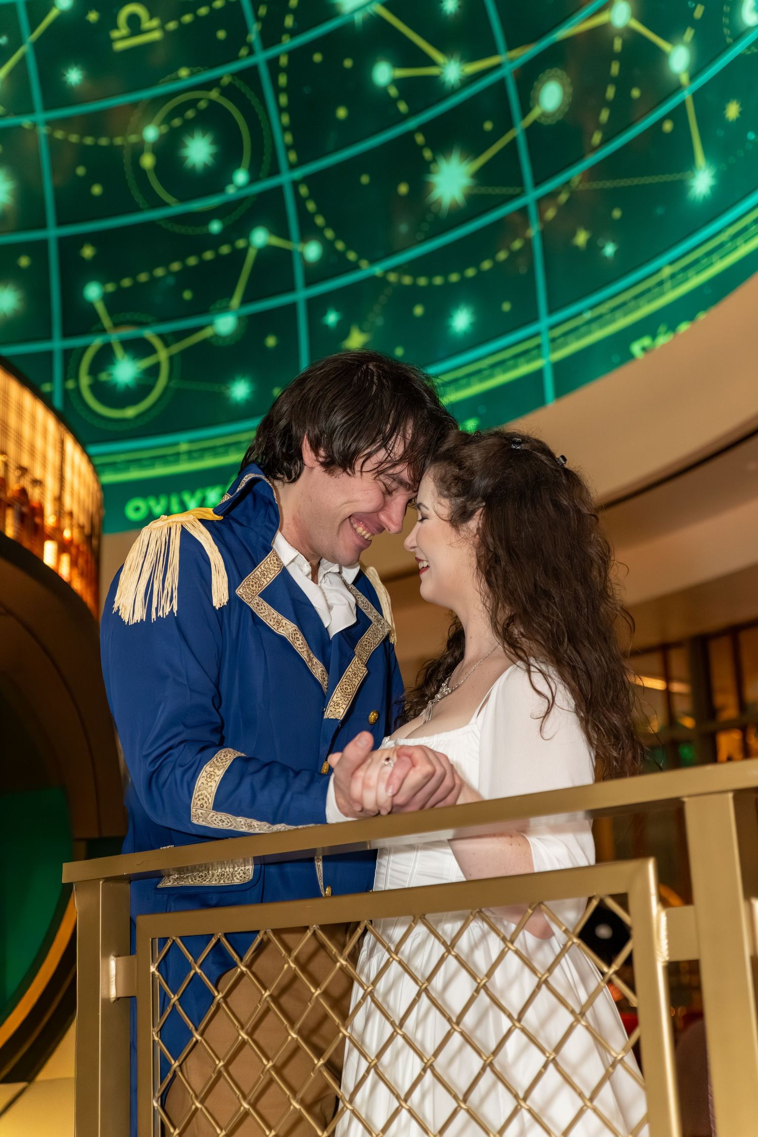 Couple in Regency-era costumes sharing a romantic moment under a glowing celestial map backdrop.
