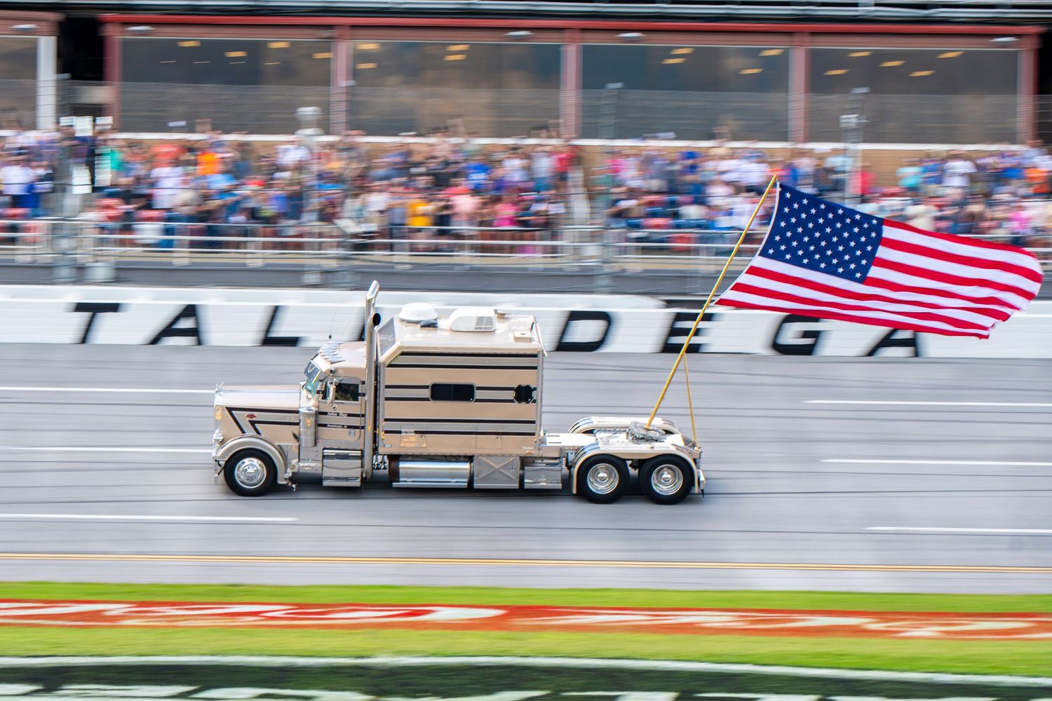 Semi truck carrying American flag drives ceremonial lap at Talladega Superspeedway.