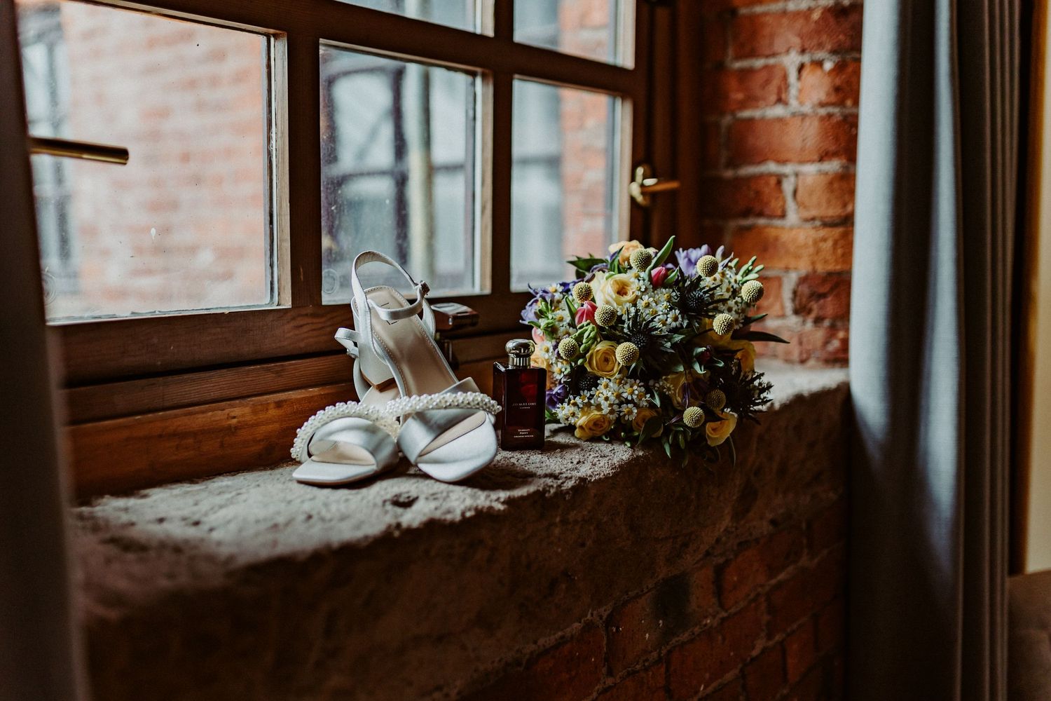 Rustic brick wall interior with vintage windows, wedding florals and bridal details on brick windowsills for Manchester City Centre wedding.
