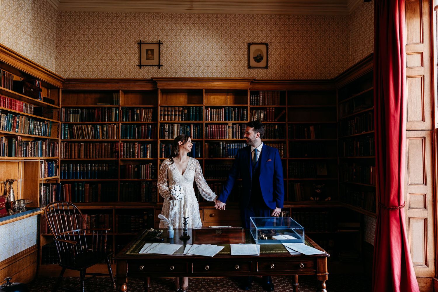 Wedding portraits at Elizabeth Gaskell's House, Manchester in the atmospheric library with vintage wallpaper and book-lined walls.