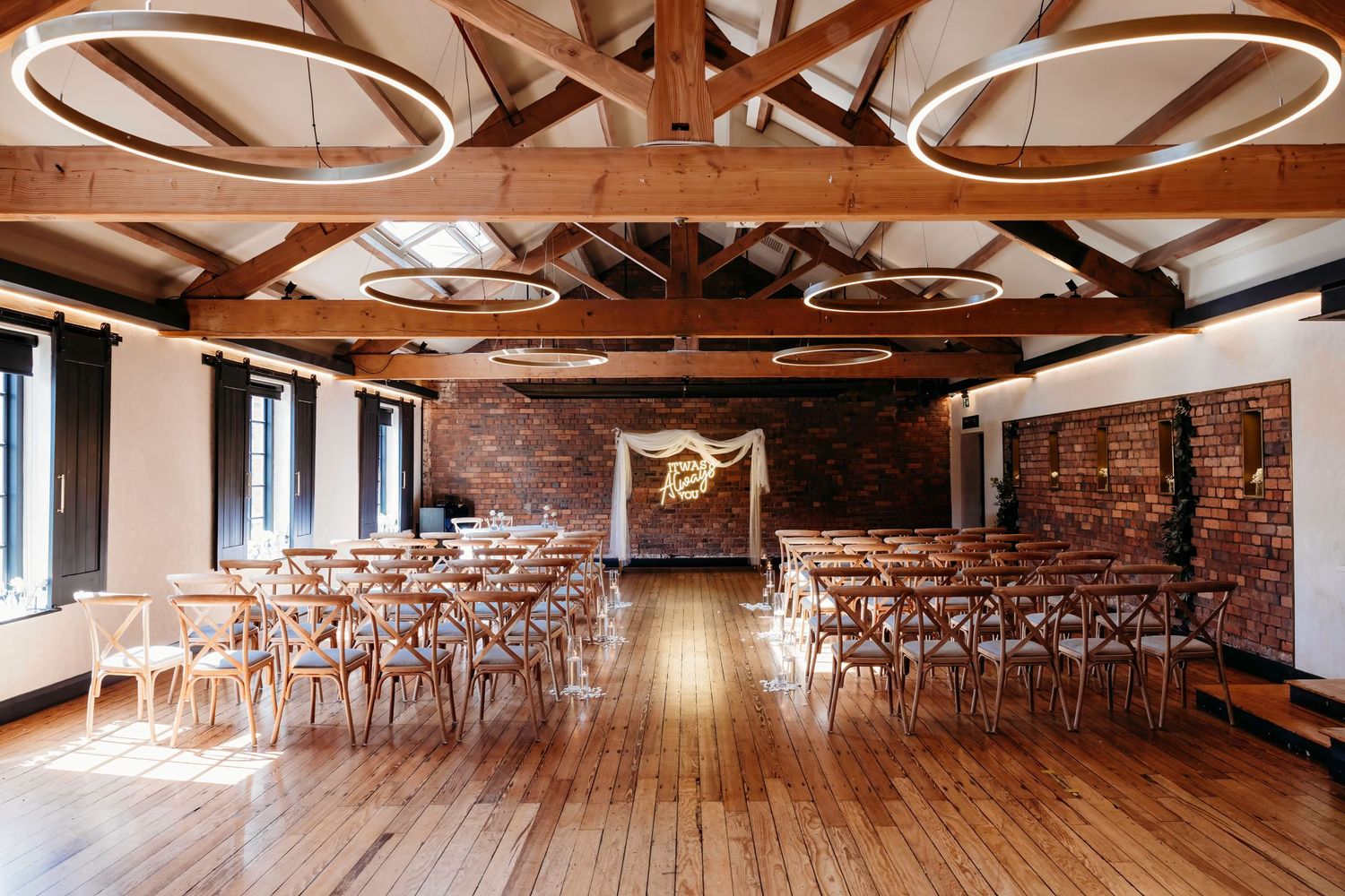 Rustic wedding venue interior with exposed wooden beams and brick walls at the Castlefield Rooms in Manchester.
