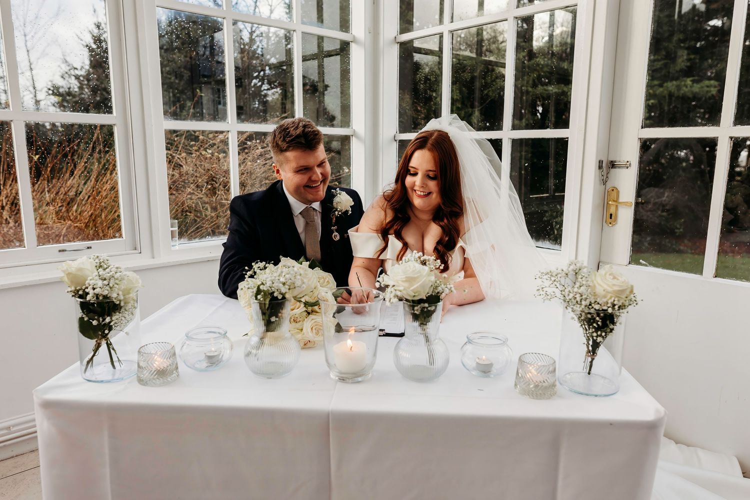 Wedding reception table decorated with white candles and floral centrepieces at Highfield Hall, Flintshire.