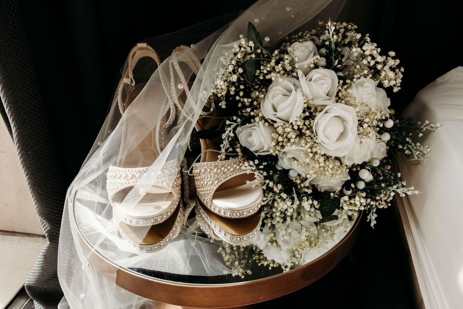 Wedding detail shots of white floral arrangements and accessories on mirrored table in Manchester City Centre.