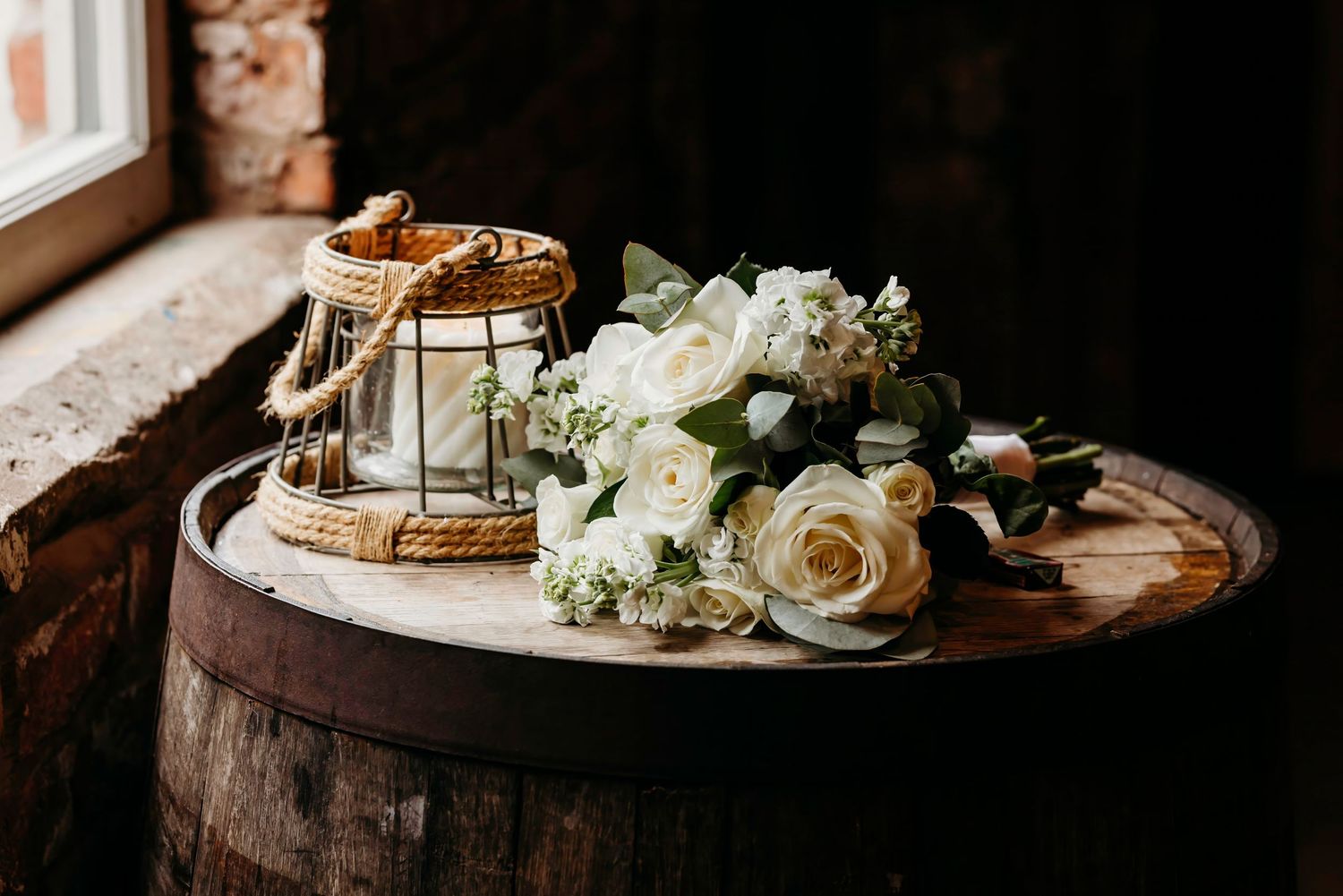 Elegant wedding detail shot of white roses and decor on rustic wooden surface at Barn at Morley's Hall Wedding Venue, Astley.