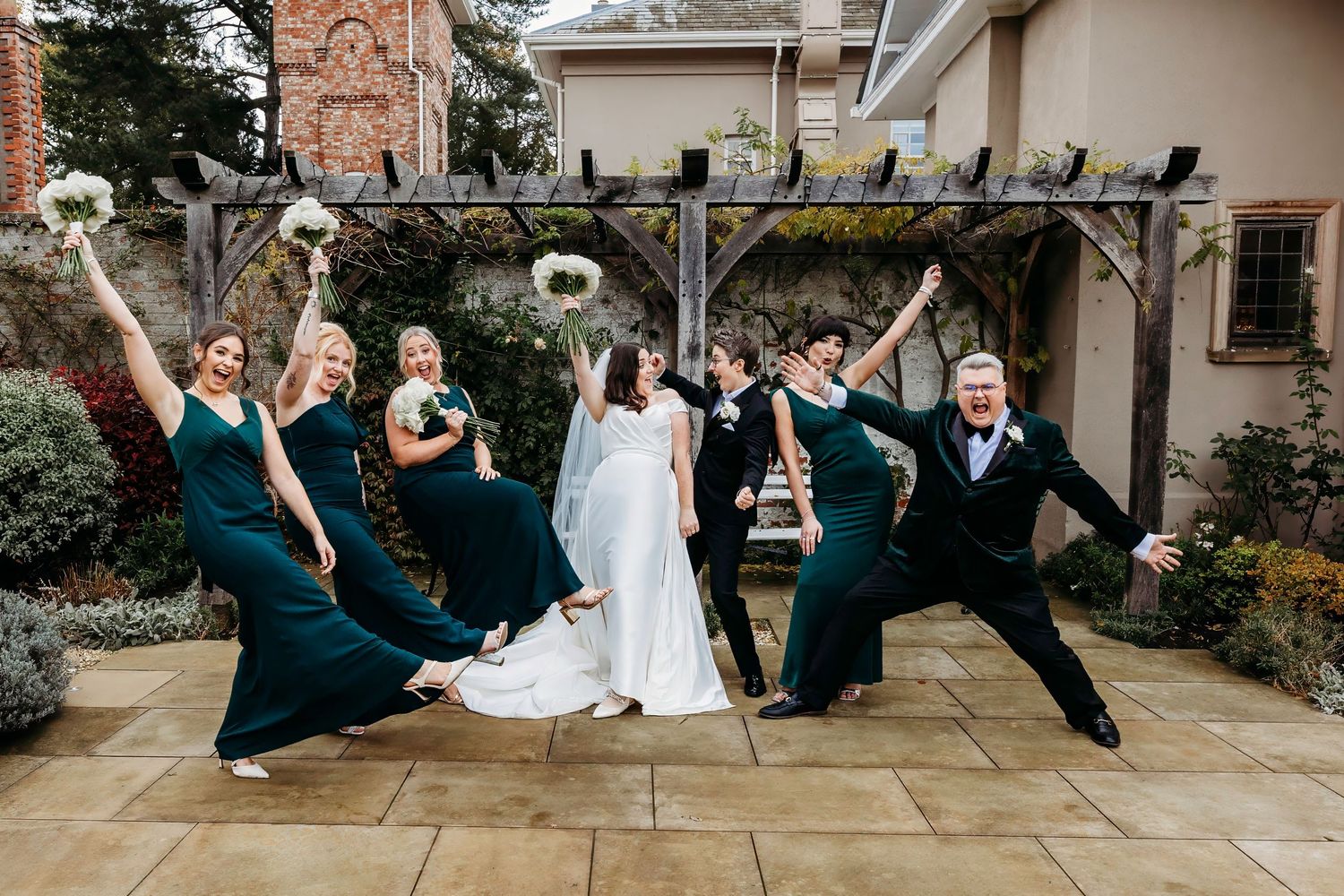 Wedding party in navy blue and white attire posing playfully outdoors at Burtonfields Hall, York.