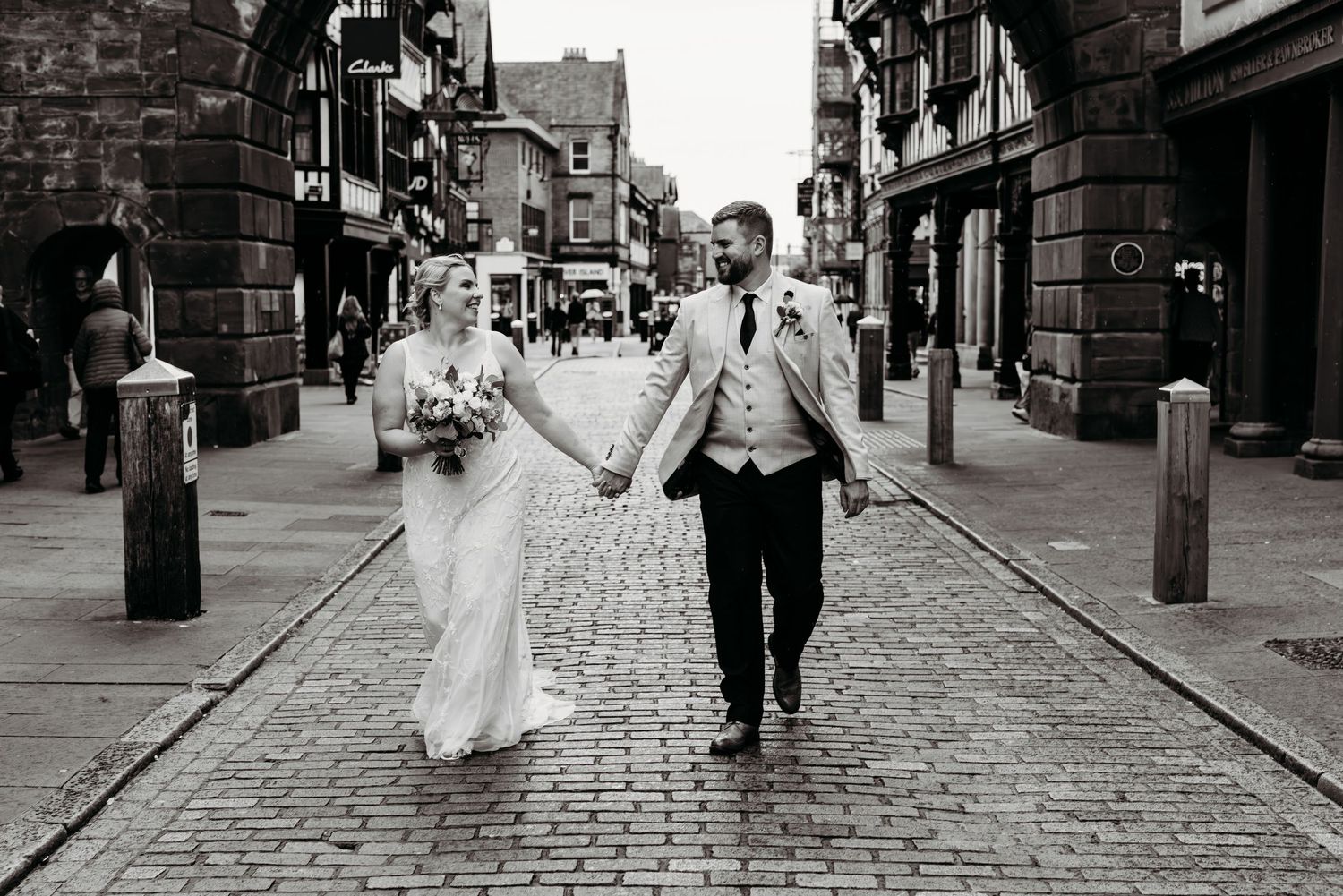 Black and white wedding photos on cobblestone streets of Chester showing romantic moments and walking scenes.