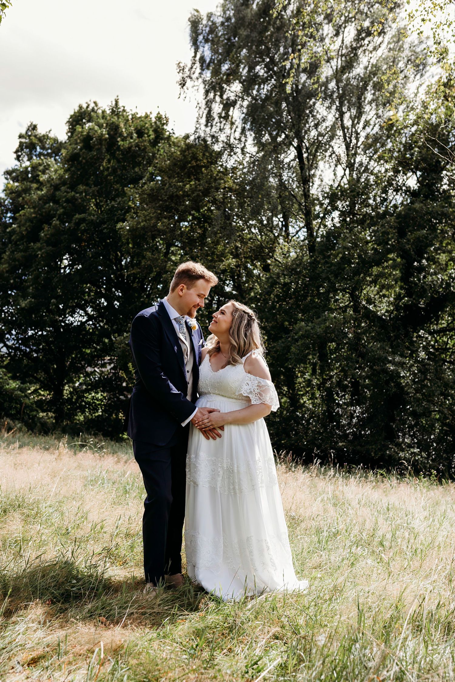 Romantic wedding portrait in a sunlit meadow with trees in the background at the Merewood Country House Hotel, Lake District wedding.