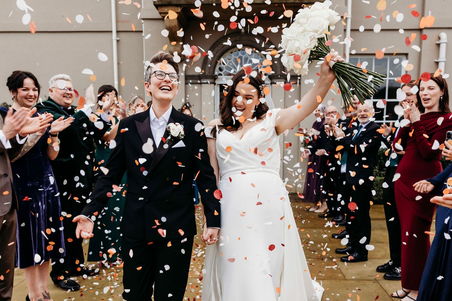 Wedding guests throw white confetti in a festive outdoor celebration sequence at Burtonfields hall, York wedding venue.