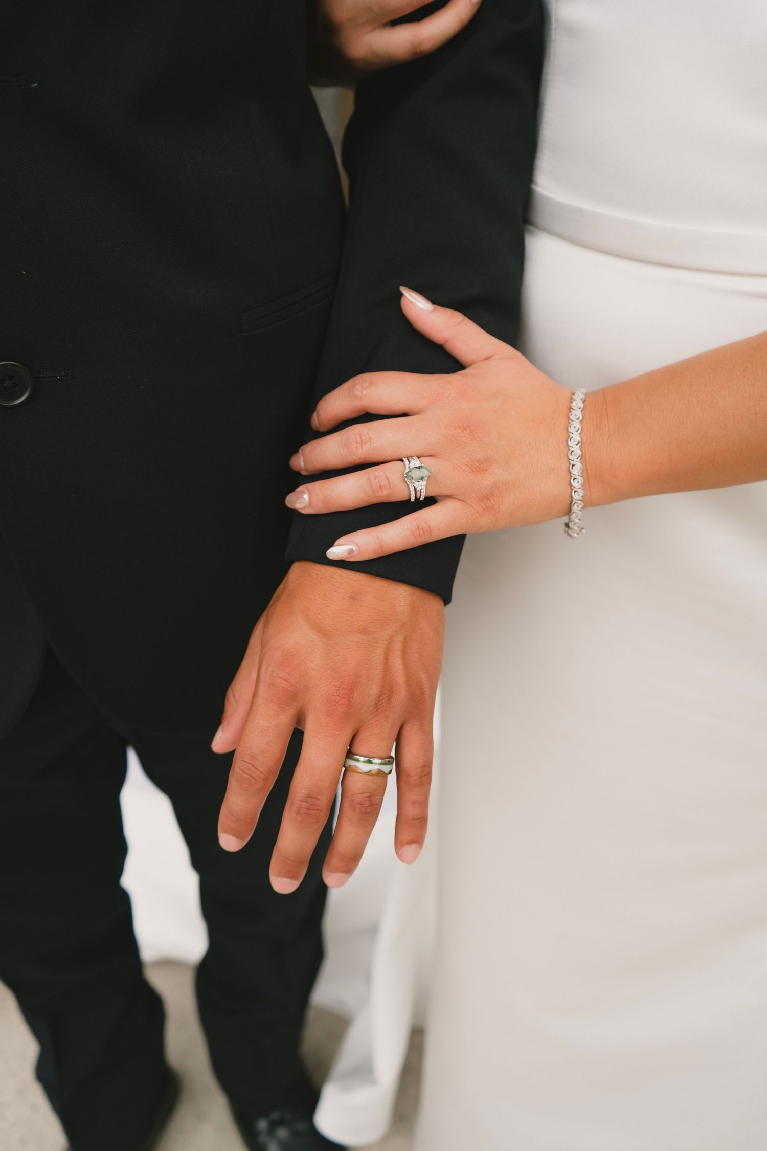 Close-up shots of hands displaying wedding rings and jewelry against a white and black background.