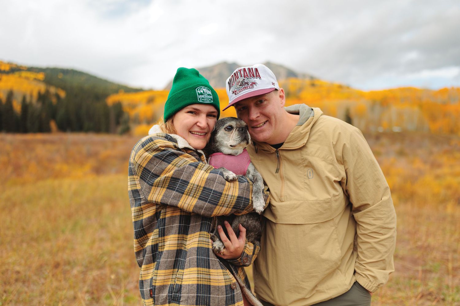 A couple embraces in a golden autumn field during a romantic engagement photoshoot at sunset.