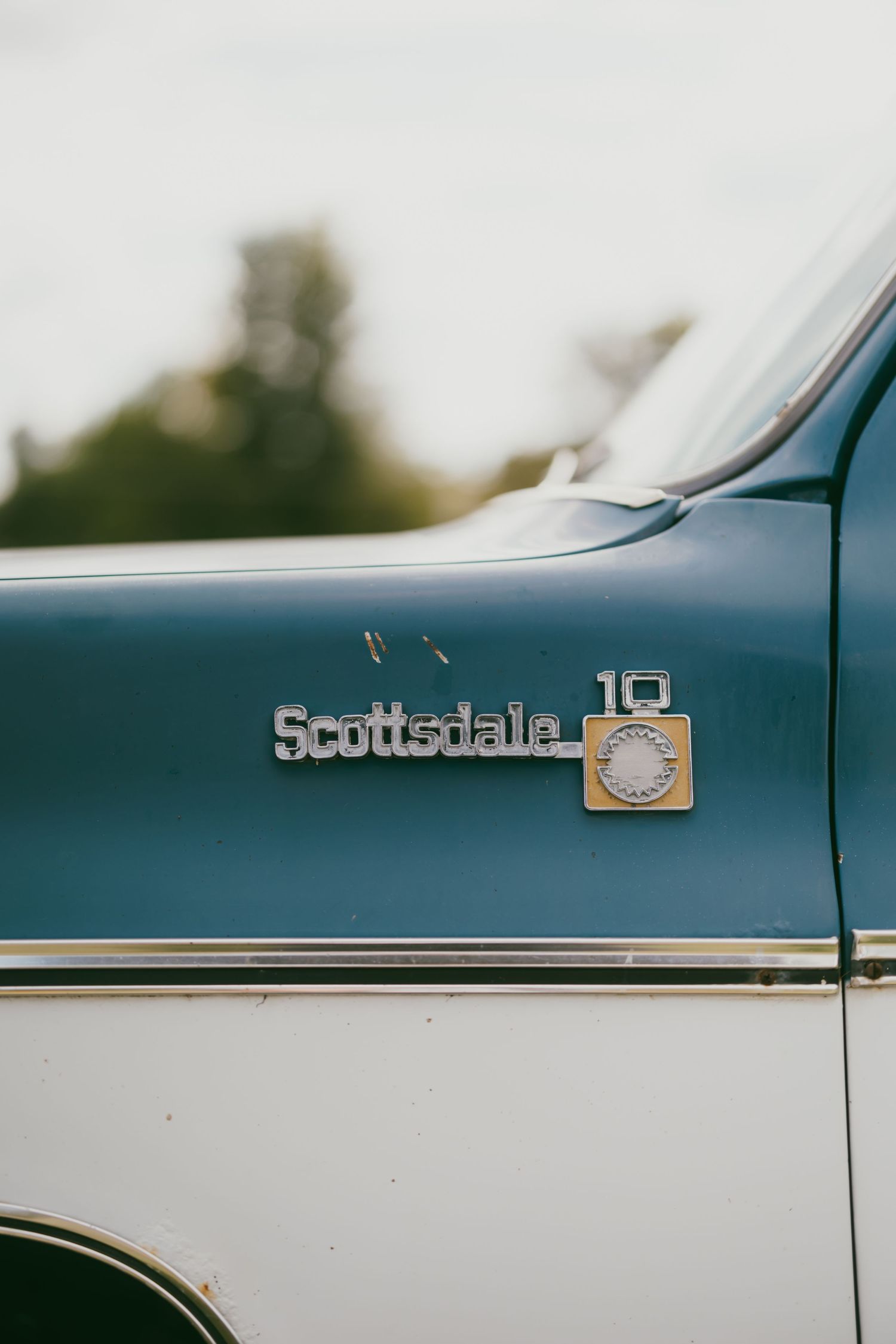 Close-up detail shot of a classic Scottsdale 10 truck emblem on blue and white paint.