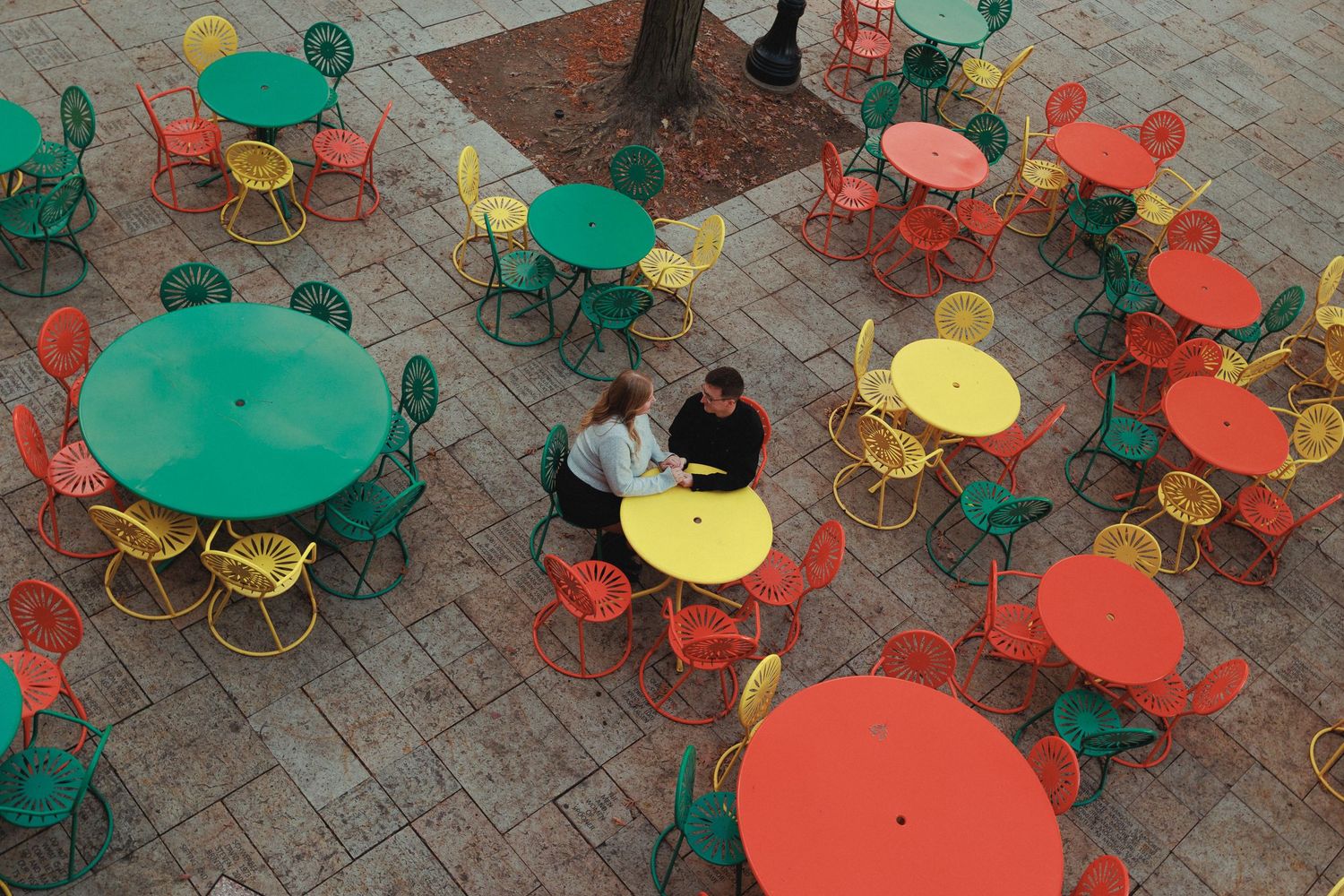 Colorful outdoor cafe seating area with green and orange tables and chairs.