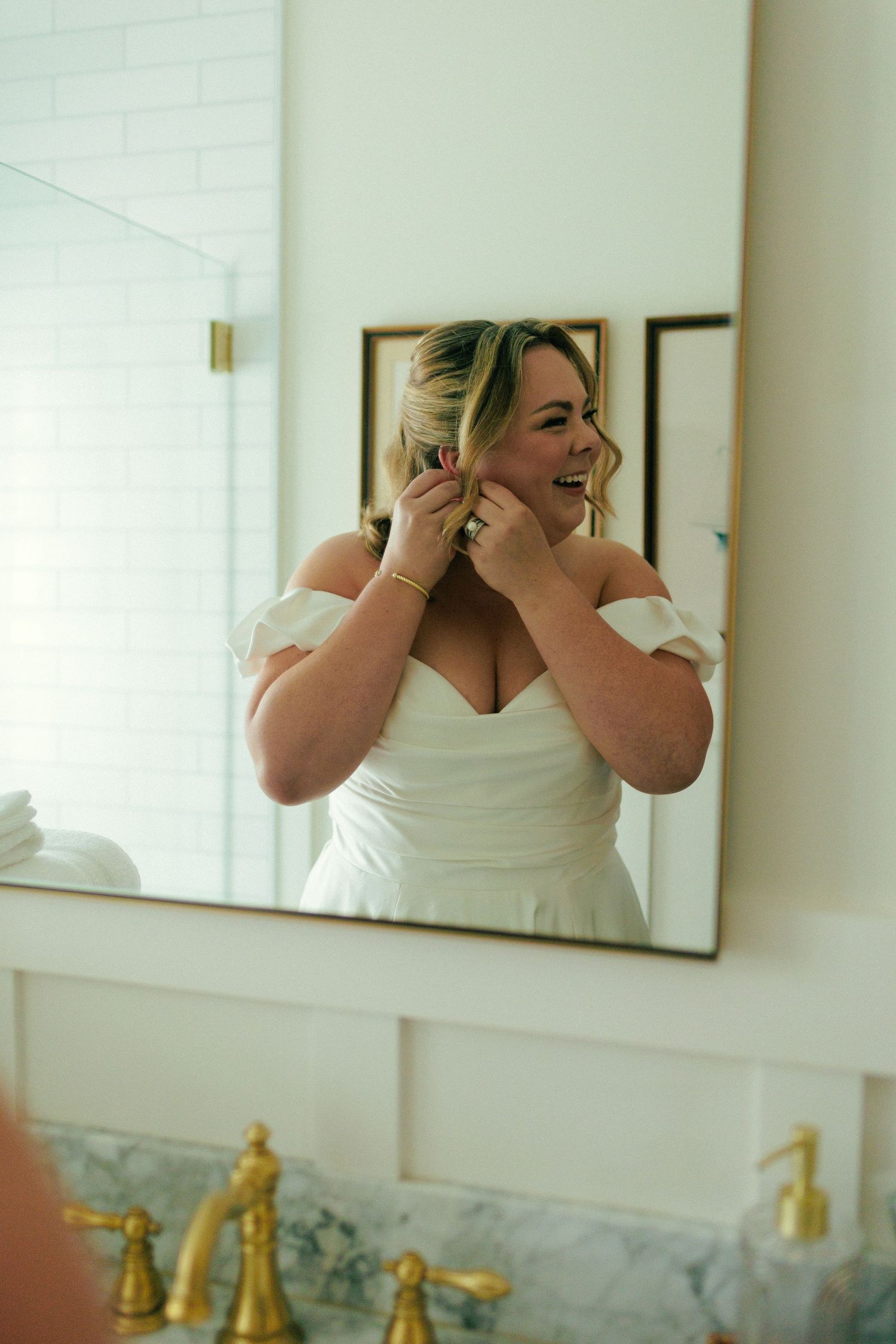 Getting ready moments reflected in bathroom mirror with bright natural light.