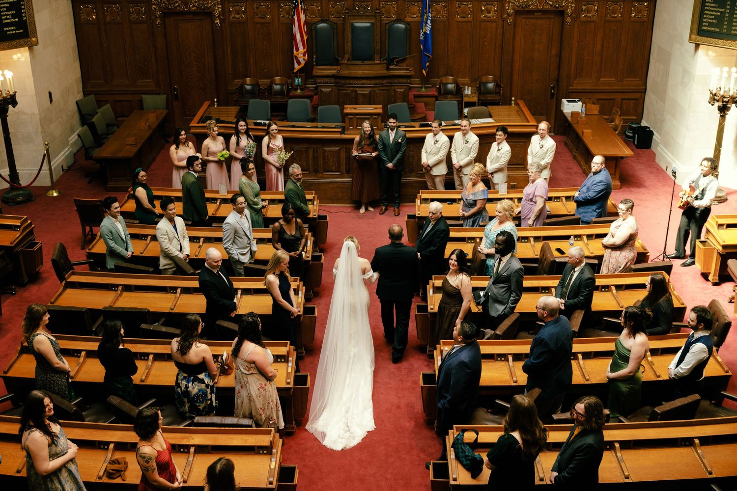 Wedding ceremony in a traditional church sanctuary with red carpeting and wooden pews.