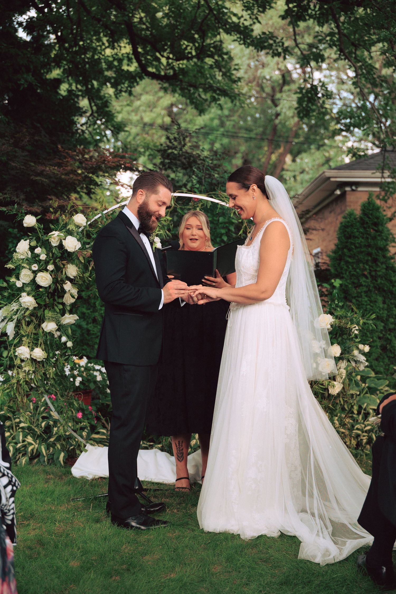 Wedding ceremony moment in garden setting with white floral arrangements.