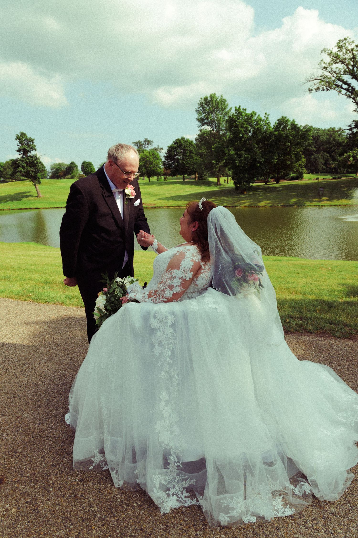 Newlyweds share a tender moment by a lake on their wedding day.