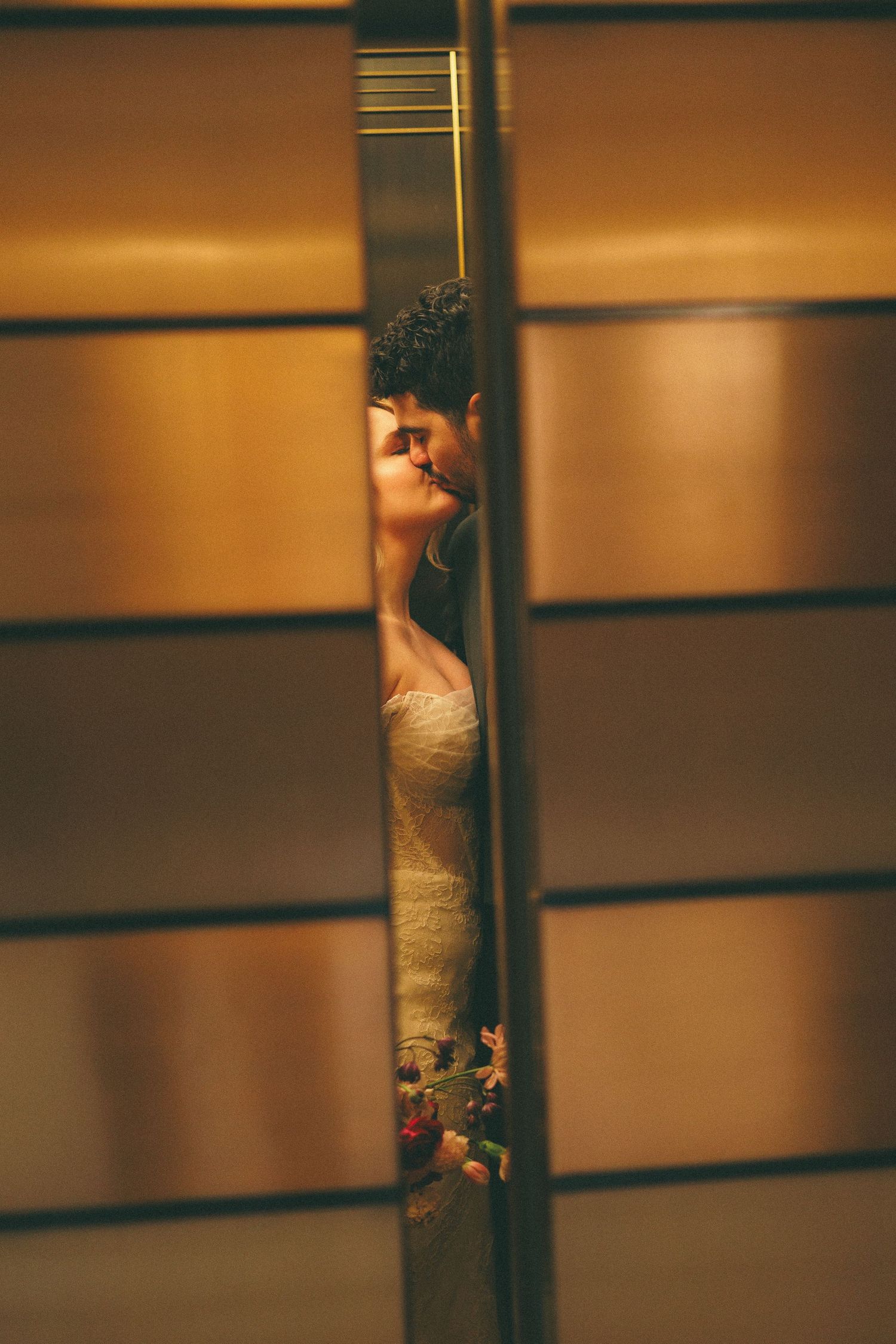 Artistic wedding photograph with warm lighting and architectural elements creating dramatic shadows.