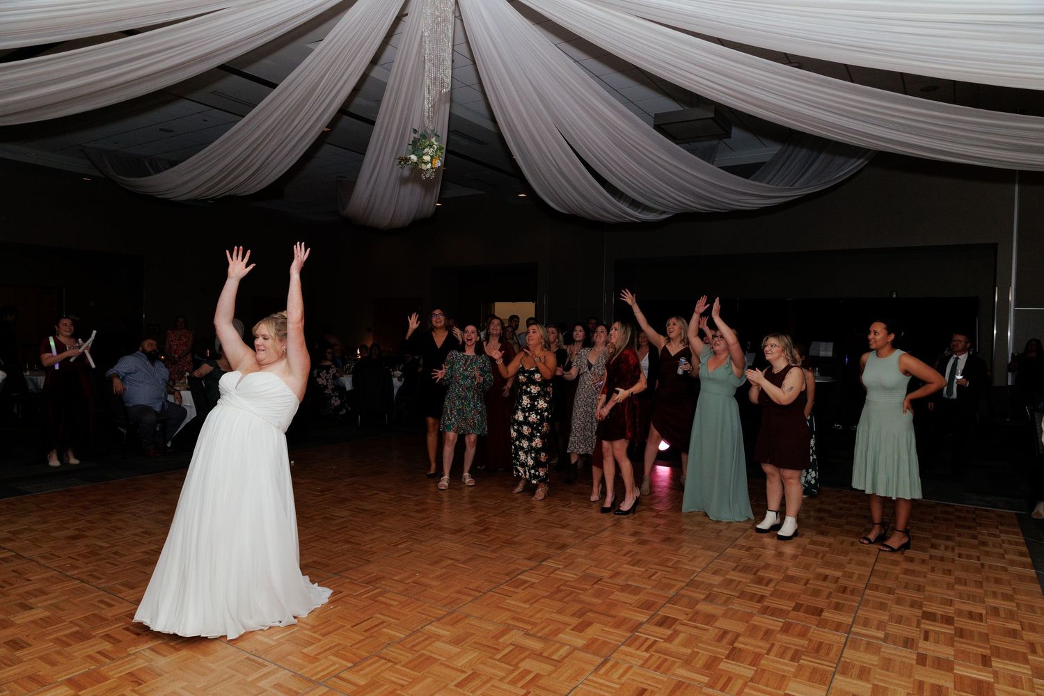 Wedding reception dance floor under draped fabric ceiling with party guests.