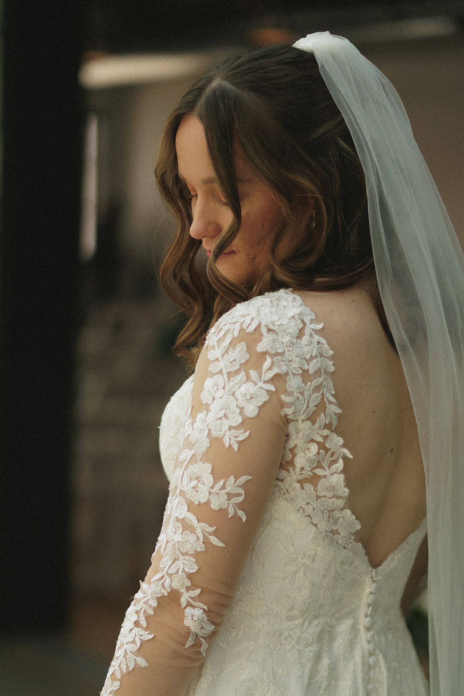 Intricate lace detail on the back of a white wedding gown with sheer sleeves.