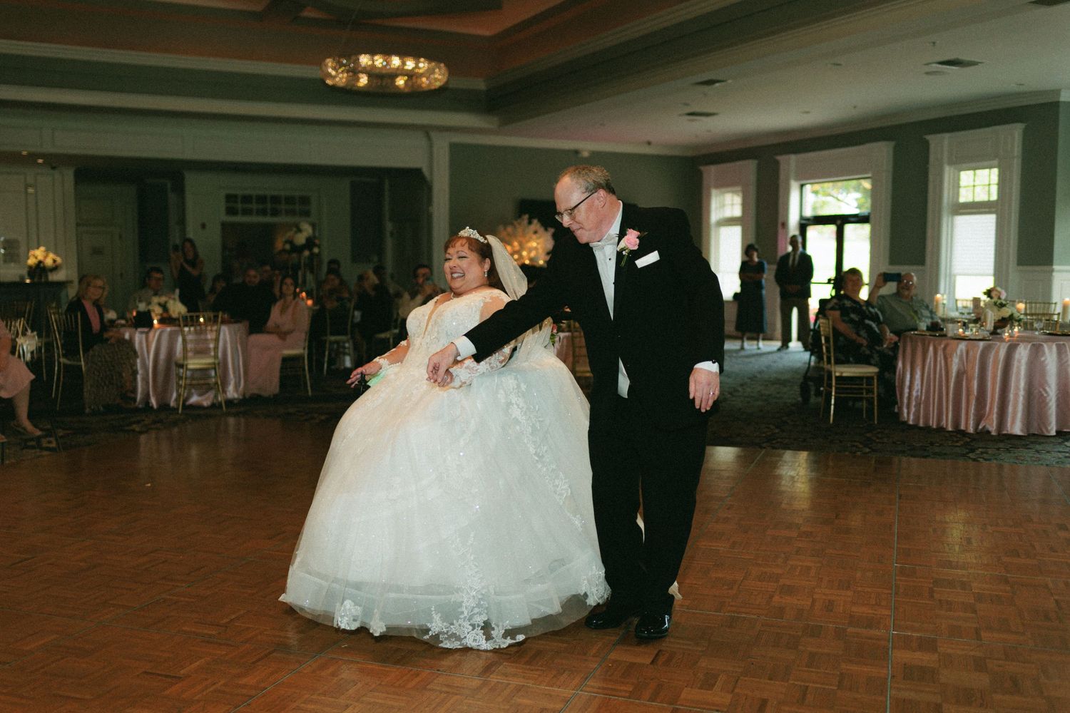 Wedding guests dance together on a brick floor during an indoor reception celebration.