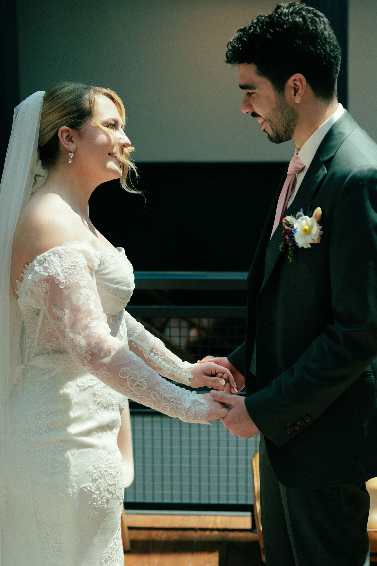 A couple exchanges vows during an intimate wedding ceremony in dramatic lighting.