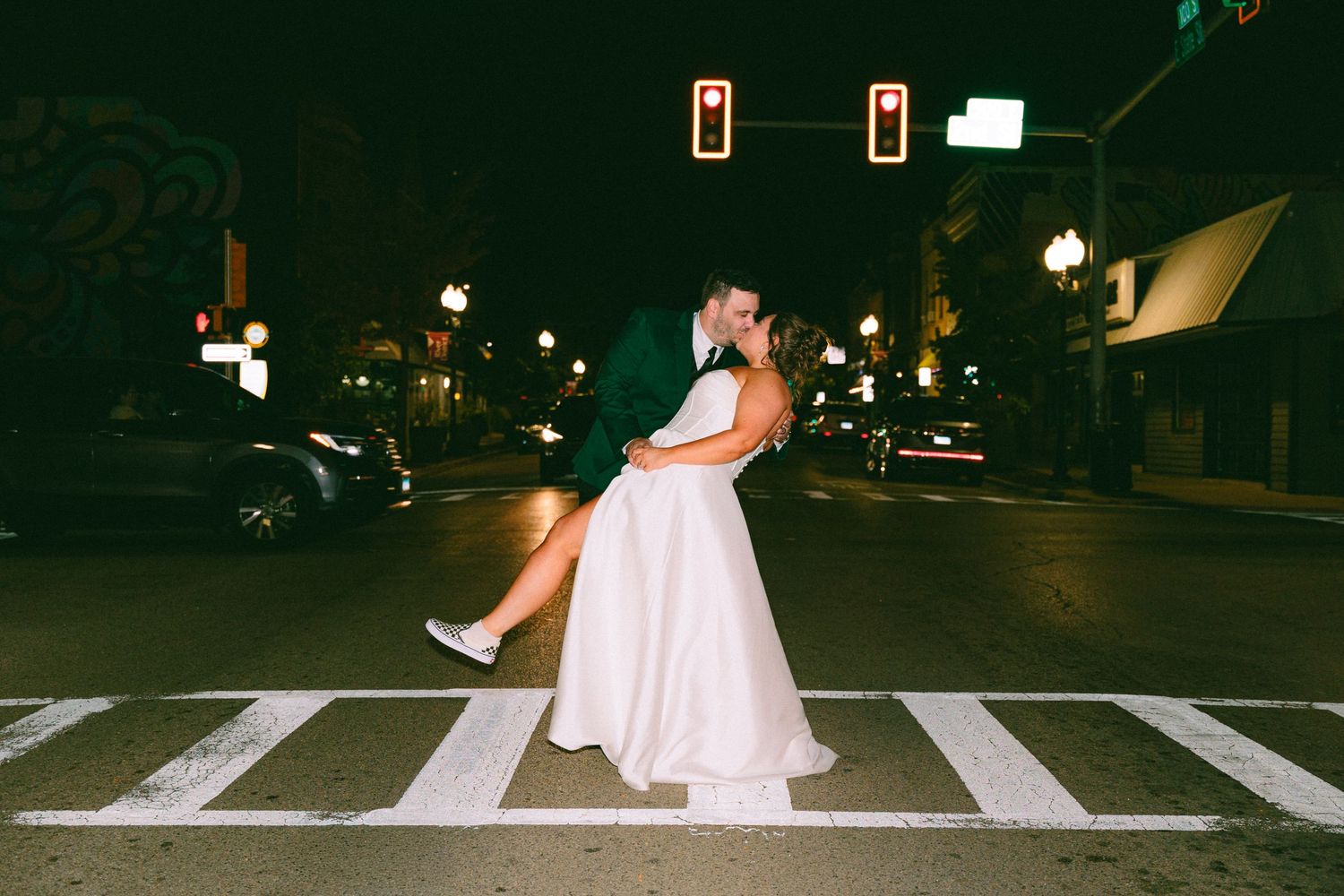 Nighttime wedding photo with couple crossing illuminated crosswalk.